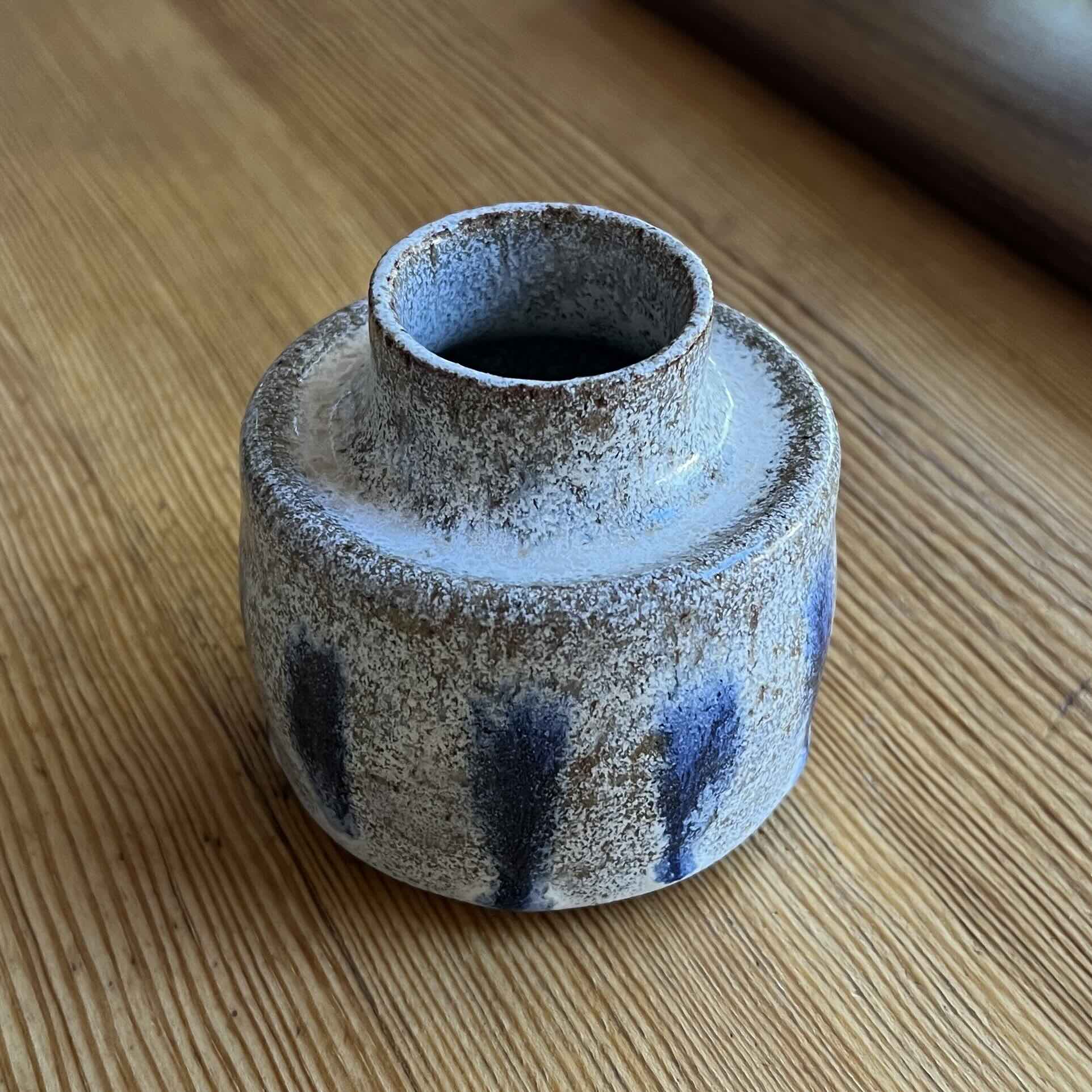 A simple bud vase with a sunken lip. Glazed a speckled white with dripping blue dots.